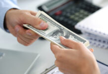 Man taking batch of hundred dollar bills. Hands close up