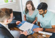 Real Estate Agent in Black Coat Discussing an Ownership Agreement to a Couple Inside the Office