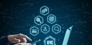 Hand with smartphone next to laptop. KYC concept