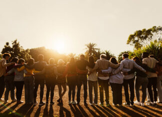 Back view of happy multigenerational people having fun in a public park during sunset time - Community and support