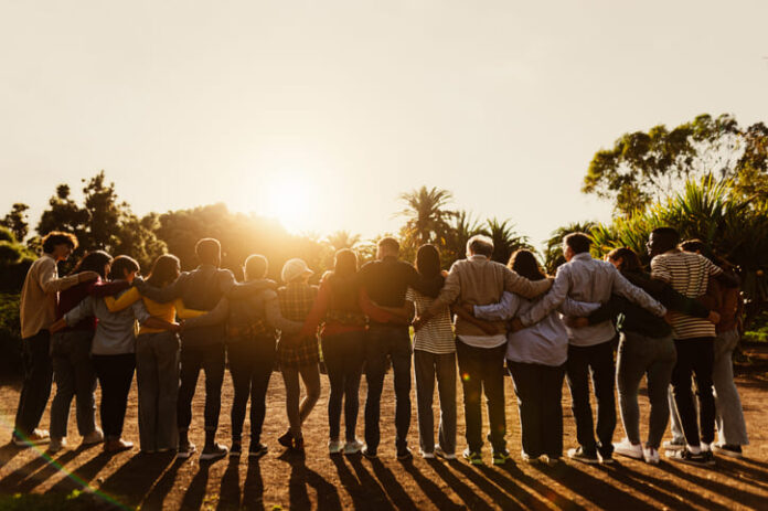 Back view of happy multigenerational people having fun in a public park during sunset time - Community and support