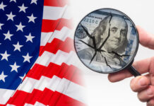 Hand with a magnifying glass in front of dollars. Crack as a symbol of US federal economy destruction