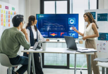 worman leader presenting a financial data and strategies in a modern office with charts and graphs displayed on a large screen