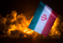 USA and Iran small flags on burning dark background. Concept of crisis of war and political conflicts between nations.