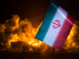 Why Trump Bombed Iran: Preserving US and Israeli Nuclear Supremacy in the Middle East USA and Iran small flags on burning dark background. Concept of crisis of war and political conflicts between nations.