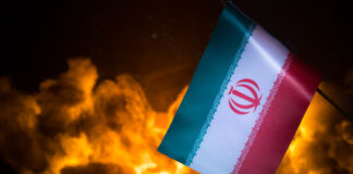 USA and Iran small flags on burning dark background. Concept of crisis of war and political conflicts between nations.