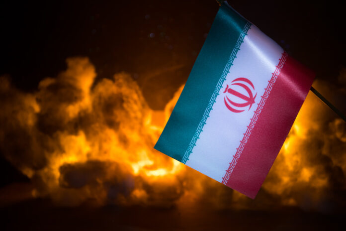 USA and Iran small flags on burning dark background. Concept of crisis of war and political conflicts between nations.