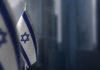 Small flags of Israel on a blurry background of the city.