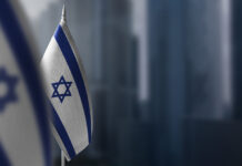 Small flags of Israel on a blurry background of the city.