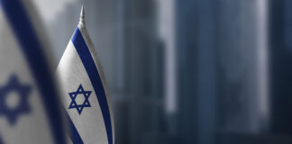 Small flags of Israel on a blurry background of the city.