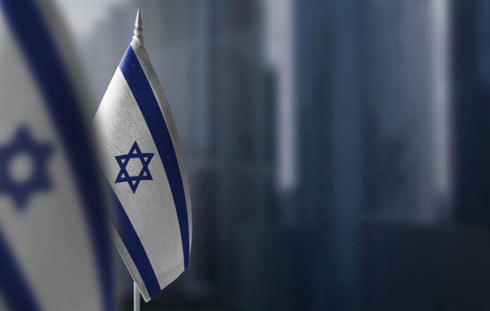 Small flags of Israel on a blurry background of the city.