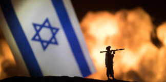 Israel small flag on burning dark background.