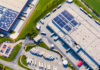 Industrial warehouses with solar panels on the roof. Technology park and factories from above