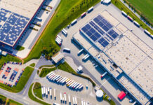 Industrial warehouses with solar panels on the roof. Technology park and factories from above