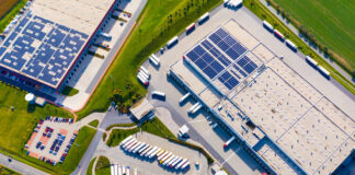Industrial warehouses with solar panels on the roof. Technology park and factories from above
