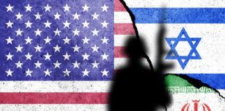 Flags of United States of America, Israel and Iran painted on the concrete wall with soldier shadow.