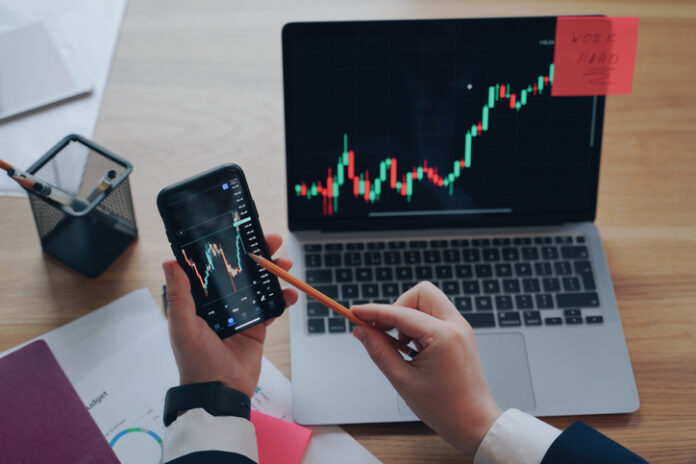 Man is analyzing business data on phone and laptop screens. Exchange trading. Hard work concept. Understanding Market Moves: A Look at Order Flow and Technical Analysis