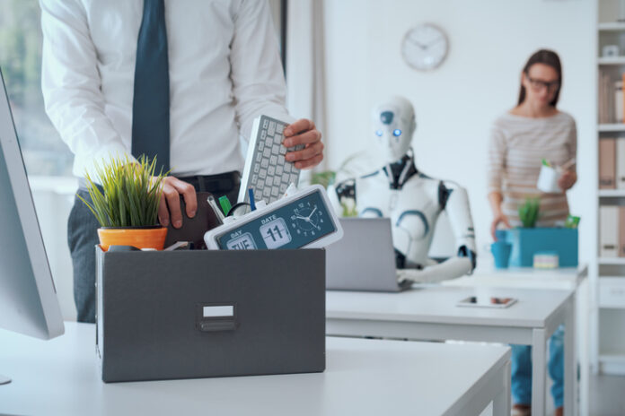 The impact of AI on jobs: fired business people leaving the office Dismissed business people packing their belongings and leaving the office, a robot is sitting at the desk and working: the impact of AI on jobs