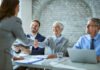 Happy member of human resource team shaking hands with female candidate on job interview in the office.