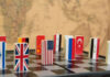 symbols of countries on the chessboard against against the background the political map of the world. Conceptual photo, political games.