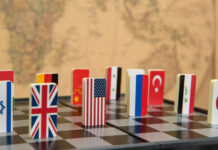 symbols of countries on the chessboard against against the background the political map of the world. Conceptual photo, political games.
