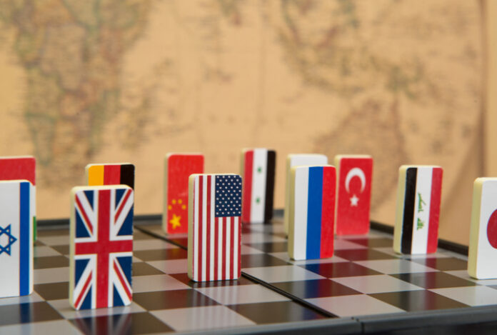 symbols of countries on the chessboard against against the background the political map of the world. Conceptual photo, political games.