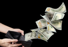 Hundred American dollars banknotes flying out of a leather wallet in male hands