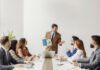 An executive standing and showing visual chart with financial report to his team of experts at boardroom.