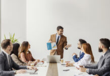 An executive standing and showing visual chart with financial report to his team of experts at boardroom.