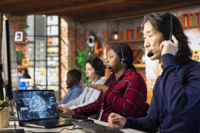 eam of multiethnic call center workers using AI chatbot to reply to common customer queries. Multiracial customer service coworkers generate automated responses to clients using AI