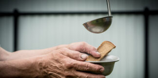 The man in the hands holding a plate and a piece of bread.