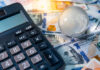 Global business and economy. World globe crystal glass and calculator on various international money banknotes.