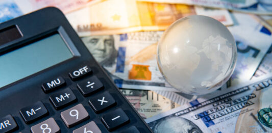 Global business and economy. World globe crystal glass and calculator on various international money banknotes.