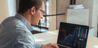 Financial analyst analyzing the trading display on computer