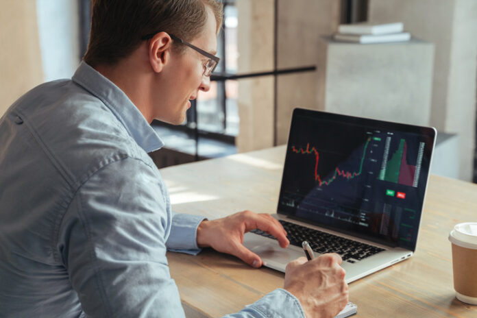 Financial analyst analyzing the trading display on computer