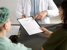 Rear view of couple of girls signing medical contract during meeting with doctor in office