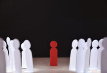 The Genesis of Israeli Utra-apartheid social discrimination concept with many little white paper men around a different one on wooden base and dark background front view