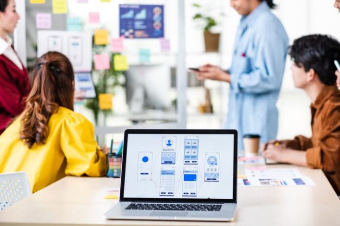 UX Designers and ui developer presenting and testing mobile app interface design on whiteboard in meeting at modern office.