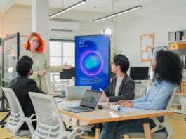 Gen AI Promise Depends On a Learning Culture Revolution Diverse business professionals male and female meet in bright office interior, using AI virtual assistant to brainstorm, connect big data dots, discuss creative strategy teamwork growth and progress