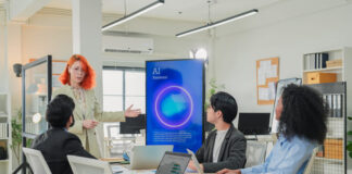 Diverse business professionals male and female meet in bright office interior, using AI virtual assistant to brainstorm, connect big data dots, discuss creative strategy teamwork growth and progress