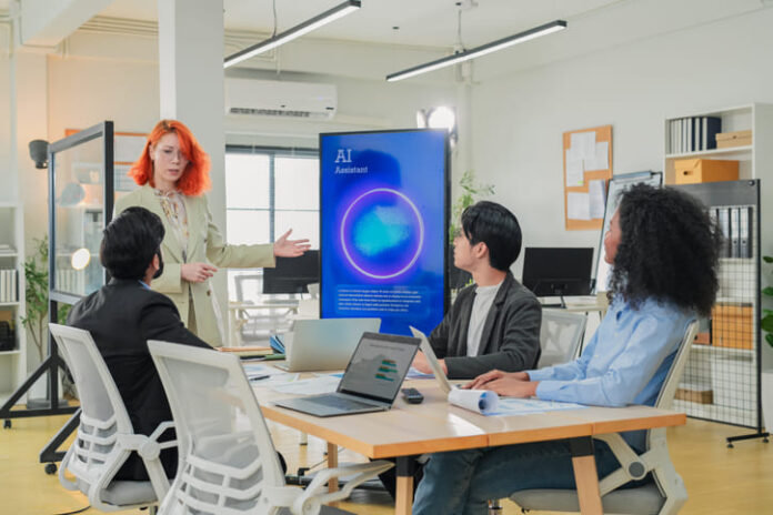 Diverse business professionals male and female meet in bright office interior, using AI virtual assistant to brainstorm, connect big data dots, discuss creative strategy teamwork growth and progress
