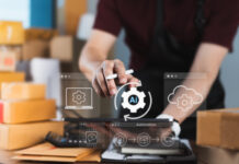 E-commerce seller activating AI-powered automation system on digital tablet, surrounded by cloud computing and logistics icons, for intelligent inventory management and streamlined fulfillment process