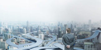 Businessman stands choosing his way on city