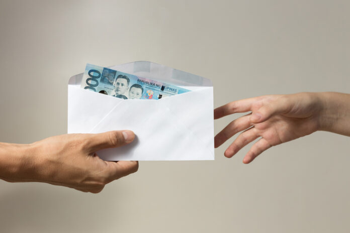 Hand holding giving cash banknote of one thousand Philippines in envelope peso paying bills, payment or bribe, salary