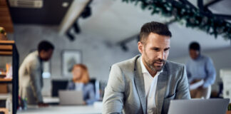 Photo of a focused businessman, dressed in a suit, working over the laptop, at the office. RTO Mirage concept