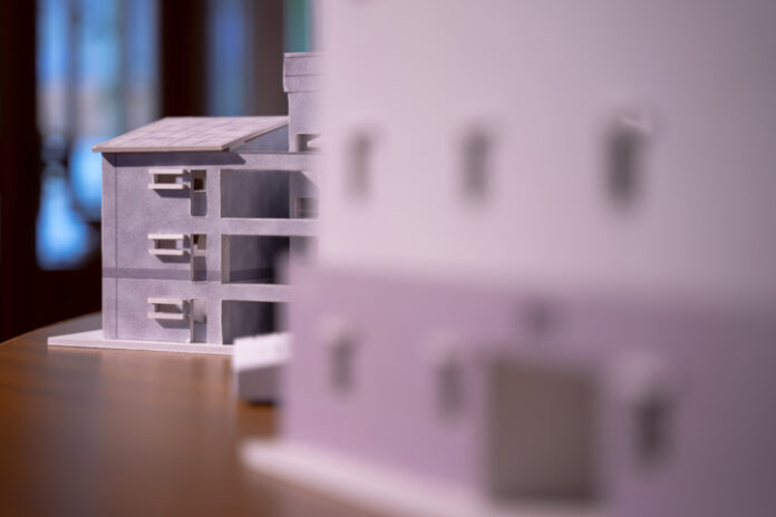 3D solitary tile roof house structure model of a residential building on bokeh light background KPI