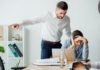 Selective focus of businessman pointing with finger near offended mexican colleague in office. Workplace Misconduct concept