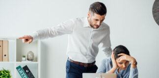 Selective focus of businessman pointing with finger near offended mexican colleague in office. Workplace Misconduct concept