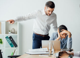 When Workplace Misconduct Allegations Create Overlapping Criminal, Regulatory and Legal Risk Selective focus of businessman pointing with finger near offended mexican colleague in office. Workplace Misconduct concept