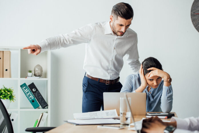Selective focus of businessman pointing with finger near offended mexican colleague in office Selective focus of businessman pointing with finger near offended mexican colleague in office. Workplace Misconduct concept